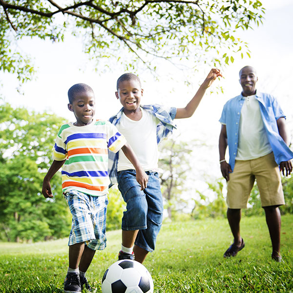 Children playing soccer with their father.